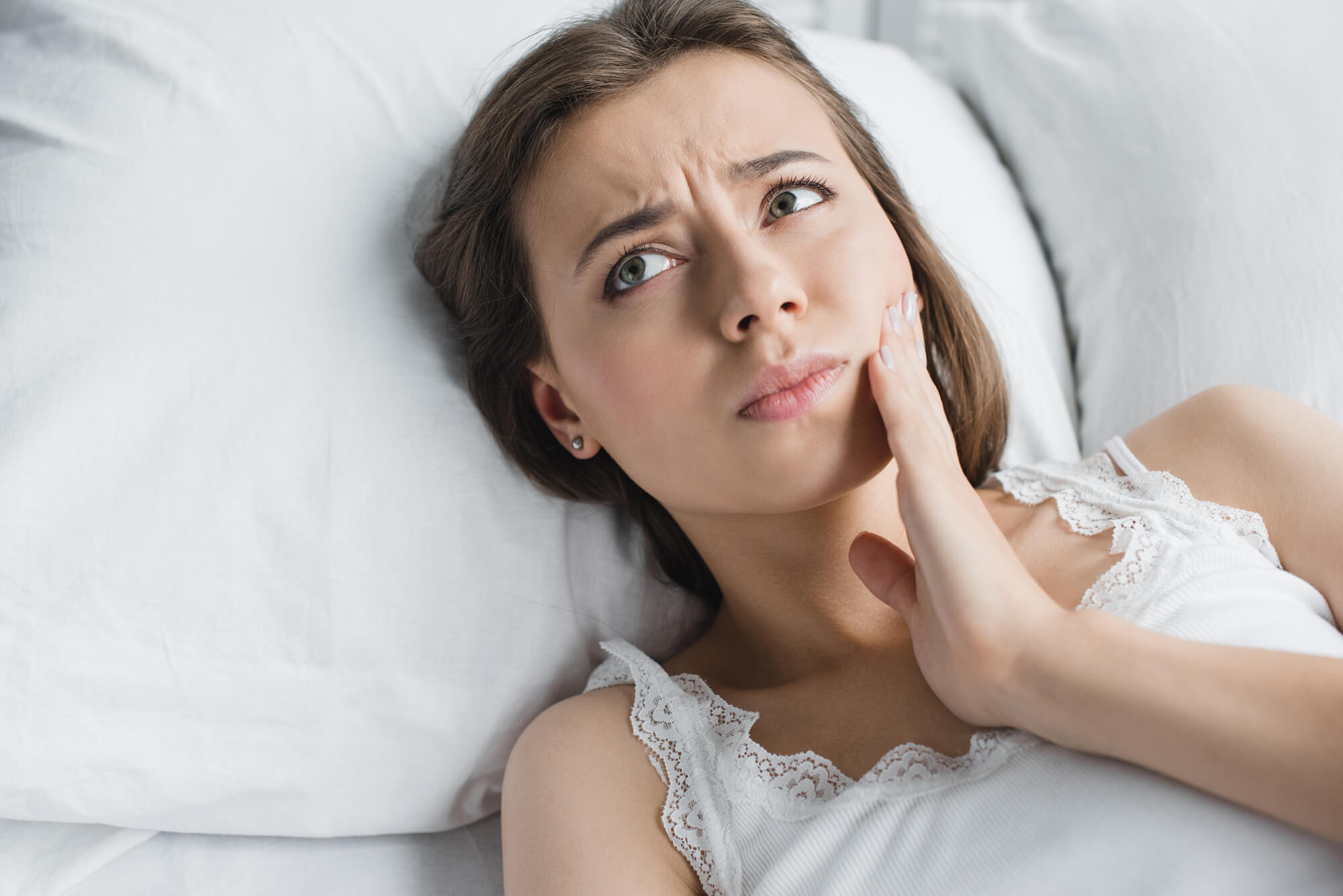 Woman lying in bed in pain after a Tooth Removal 76210
