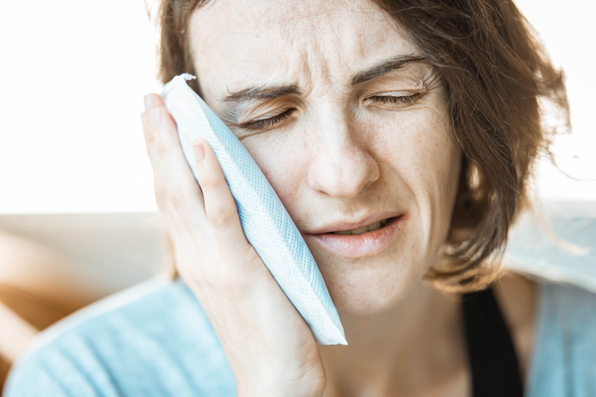 Woman holding icepack to her face after Oral Trauma Denton